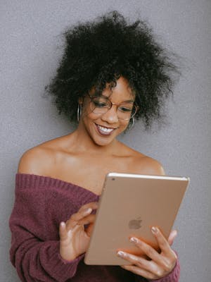 Woman In Purple Off Shoulder Top Holding An Ipad, reading the sci-fi novel Lord Ungūpūlū, set in the Andromeda galaxy.