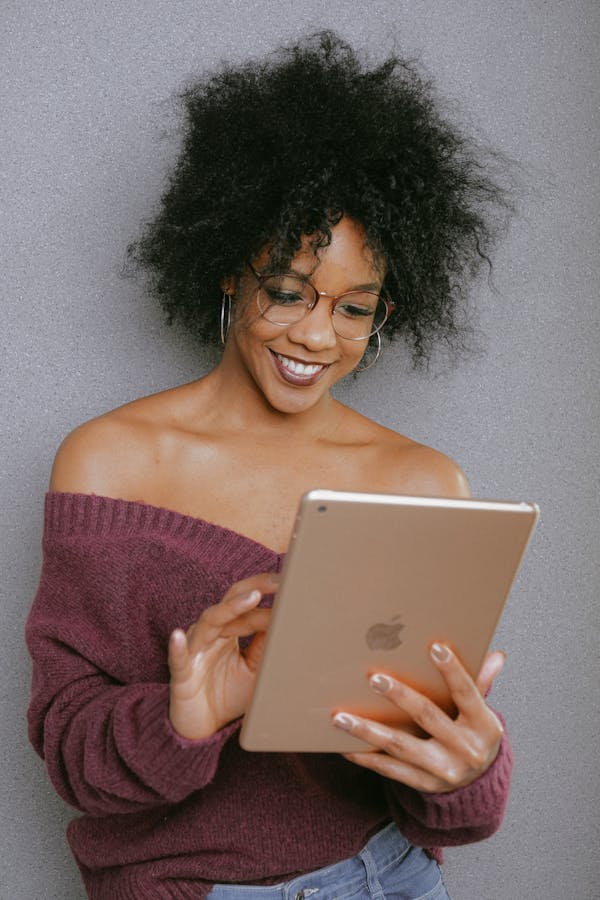 Woman In Purple Off Shoulder Top Holding An Ipad, reading the sci-fi novel Lord Ungūpūlū, set in the Andromeda galaxy.